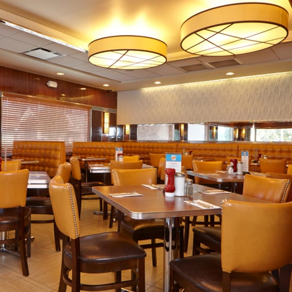 Interior of Jax Inn Diner with empty tables, brown booths, and chairs under warm lighting.
