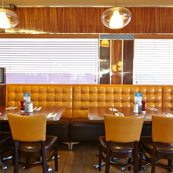 Interior of Jax Inn Diner with orange booths, wooden tables, and chairs, under modern pendant lights.