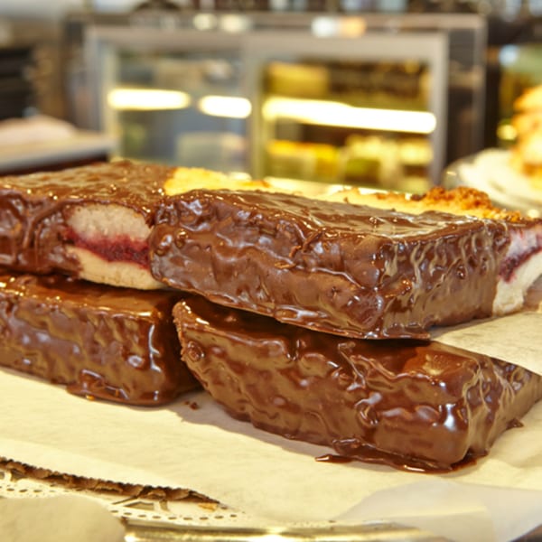Chocolate-covered pastries with a visible raspberry filling on a white paper-lined tray at Jax Inn Diner.
