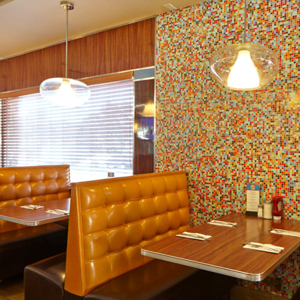 Interior of Jax Inn Diner with orange booths, wood-paneled walls, and a colorful mosaic wall.